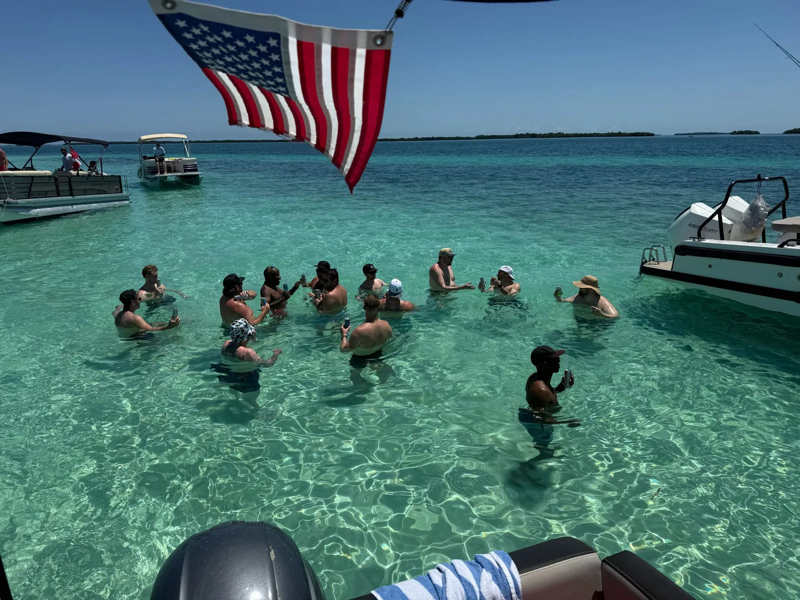 Group of Six Fins guests standing in clear turquoise water at the Snipes Point sandbar near Key West