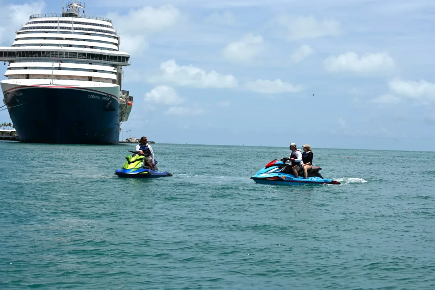 Two Six Fins jet skis riding past a Carnival cruise ship docked at the Key West cruise port